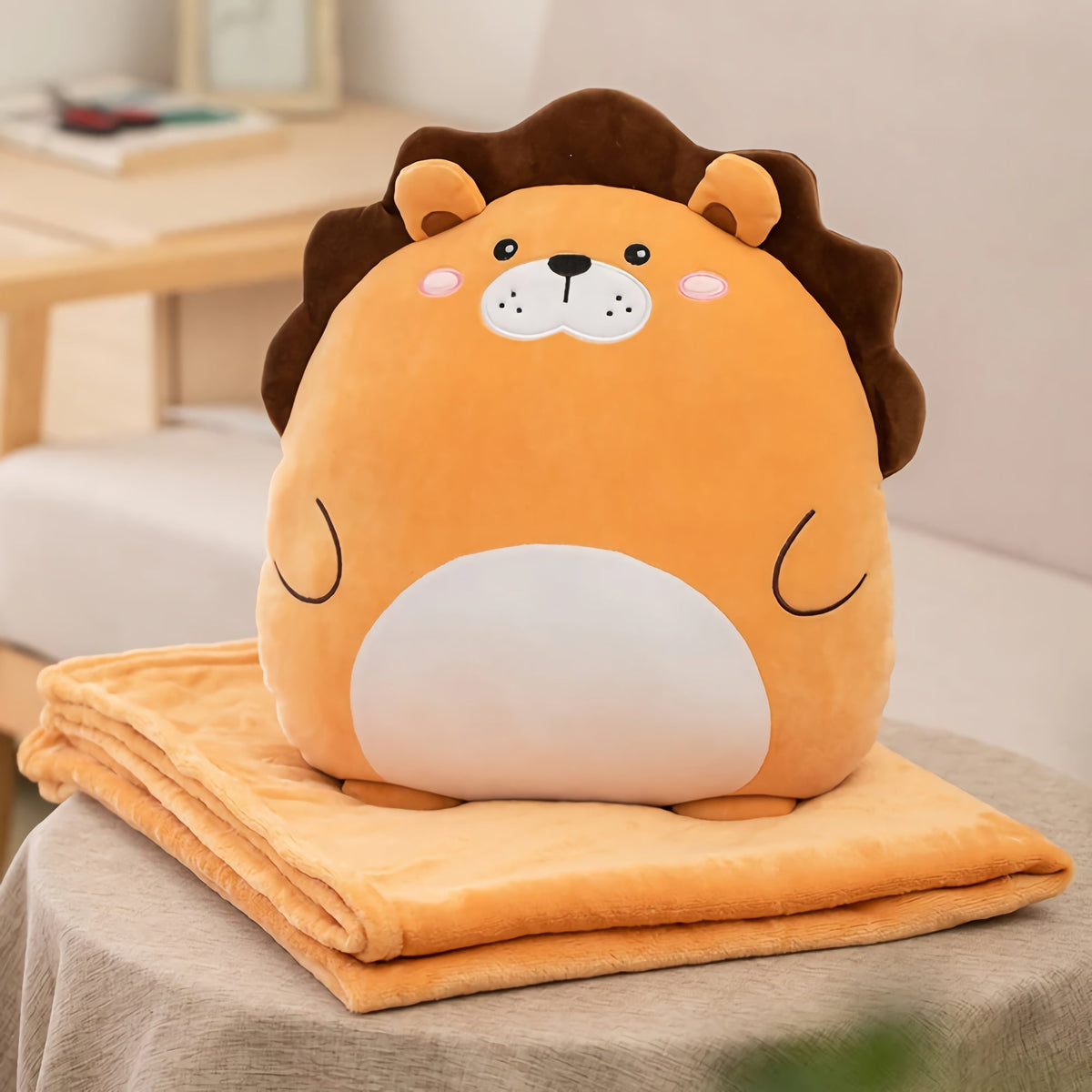 A plush lion pillow sitting folded on top of its matching travel blanket, showing the finished folded shape of a 2-in-1 blanket-plush set