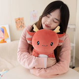Girl hugging a burgundy baby axolotl dragon plush with small cream horns on a sofa