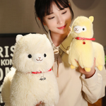 Girl holding a yellow alpaca plush next to a white alpaca plush with a red bell collar