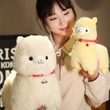 Girl holding a yellow alpaca plush next to a white alpaca plush with a red bell collar