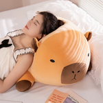 Woman sleeping on a chubby orange capybara plush pillow on a white bed