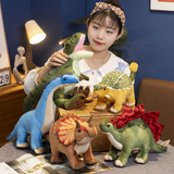 Woman with all Dinosaur Friends Plush; holding green Tyrannosaurus Rex, next to blue Brachiosaurus.