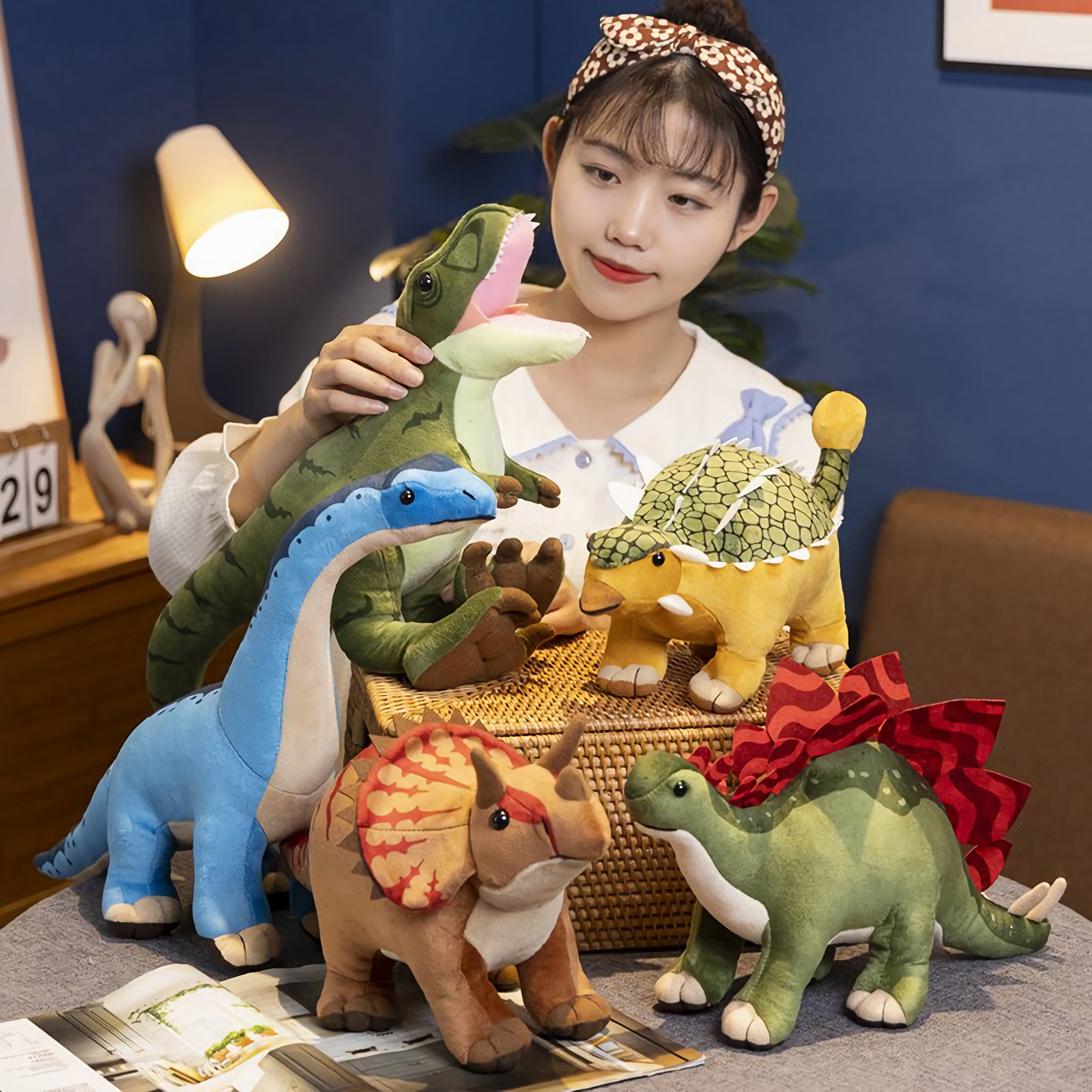 Woman with all Dinosaur Friends Plush; holding green Tyrannosaurus Rex, next to blue Brachiosaurus.