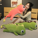 Woman on bed holding pink dinosaur plush, with two green dinosaur plushes lying beside her.