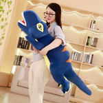 Woman with glasses hugging a long blue T-Rex plush pillow in a bright living room
