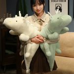 Woman holding white and mint green dragon plush body pillows with antler-like horns.