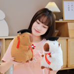Woman holding a brown and a white graduation capybara plush with black caps