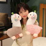 Woman holding a gray and a pink alpaca plush with music headphones and leaf sprouts