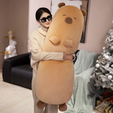 Woman hugging a tall tan capybara bolster pillow in a cozy room
