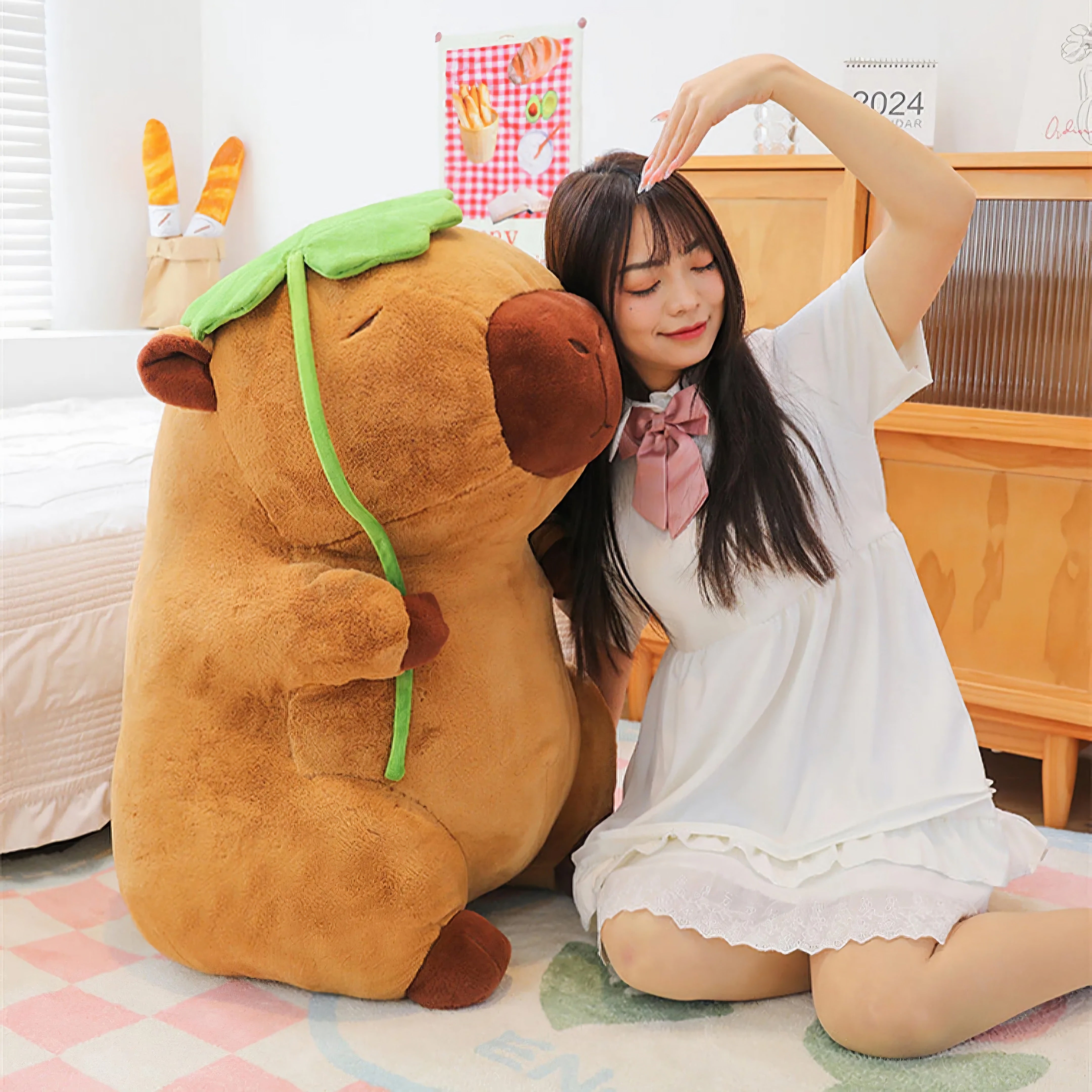 Woman posing beside a big capybara plush holding a green lotus leaf
