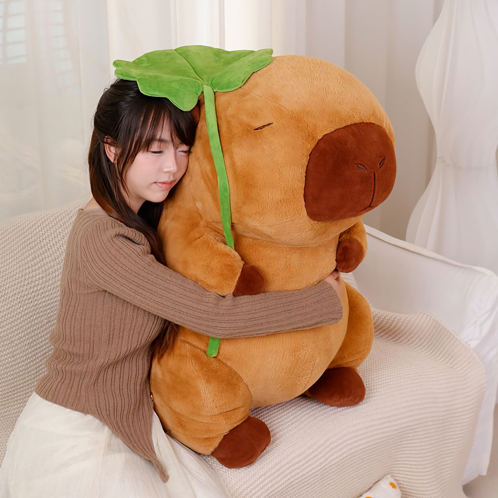 Woman hugging a capybara plush holding a green lotus leaf