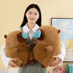 Woman holding two brown capybara plushies with blue nose bubbles