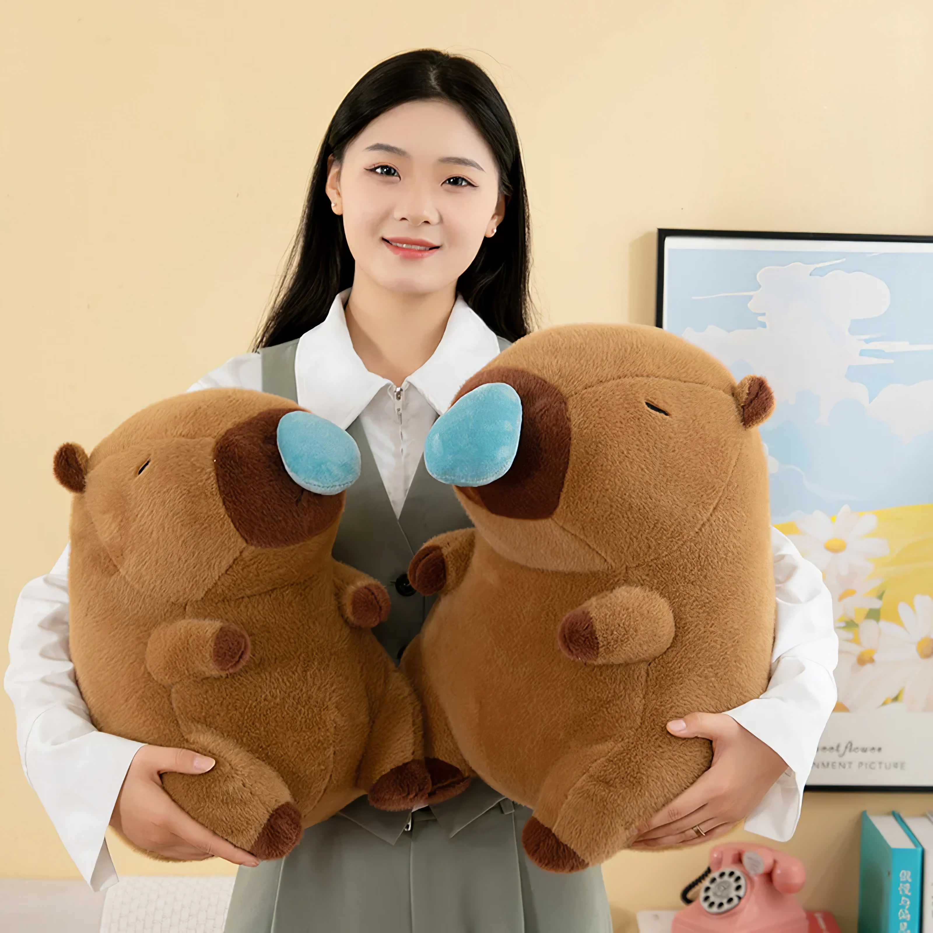 Woman holding two brown capybara plushies with blue nose bubbles