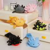Six axolotl plushies in black, pink, yellow, spotted green, blue and gray on a white shelf