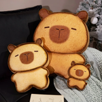 Bread capybara plushies in three sizes on a dark sofa