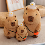 Three capybara plushies with white ducks on their heads and orange charms on a rug