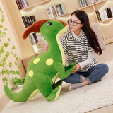 Woman with glasses sitting on a rug with a green spotted Parasaurolophus dinosaur plush