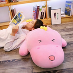 Girl lying on the floor reading with her head on a pink dinosaur plush pillow