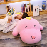 Girl lying on the floor reading with her head on a pink dinosaur plush pillow