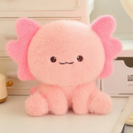 Close-up of a fluffy pink axolotl plush with a tiny stitched smile on a shelf