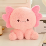 Close-up of a fluffy pink axolotl plush with a tiny stitched smile on a shelf