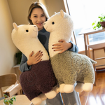 Woman hugging a purple body alpaca plush and a green body alpaca plush