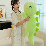 Woman holding a green giant dinosaur plush body pillow in a living room setting.