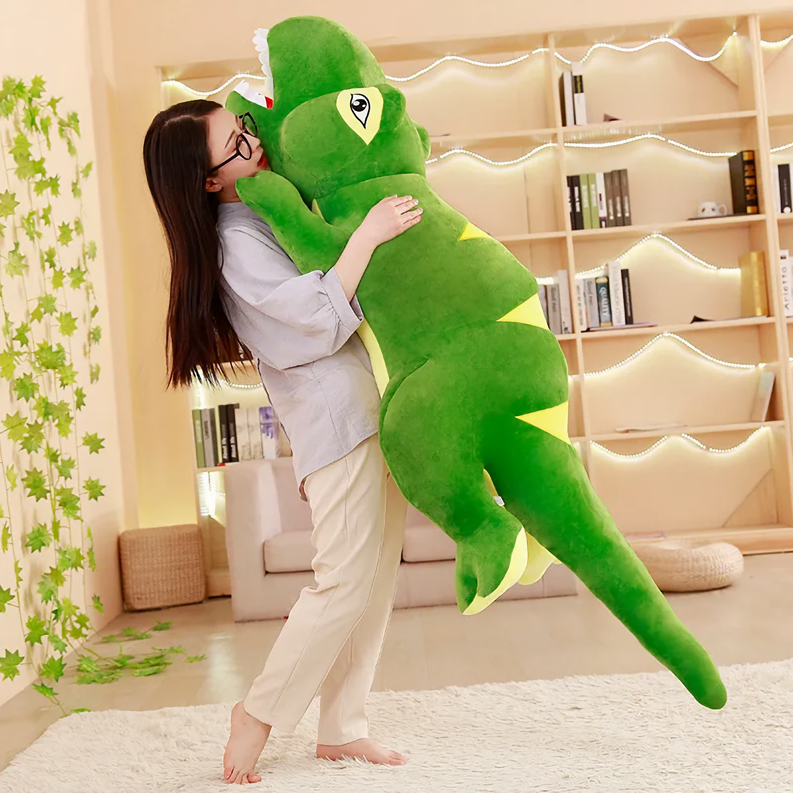 Woman hugging a long green T-Rex plush pillow upright