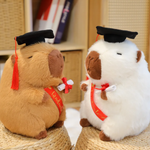 Brown and white graduation capybara plushies with black caps and red sashes on woven stools