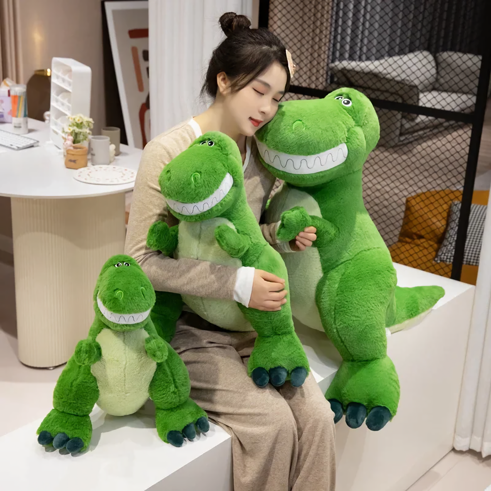 A woman hugs two green T-Rex plush toys on a bench, with a smaller T-Rex plush sitting beside her.