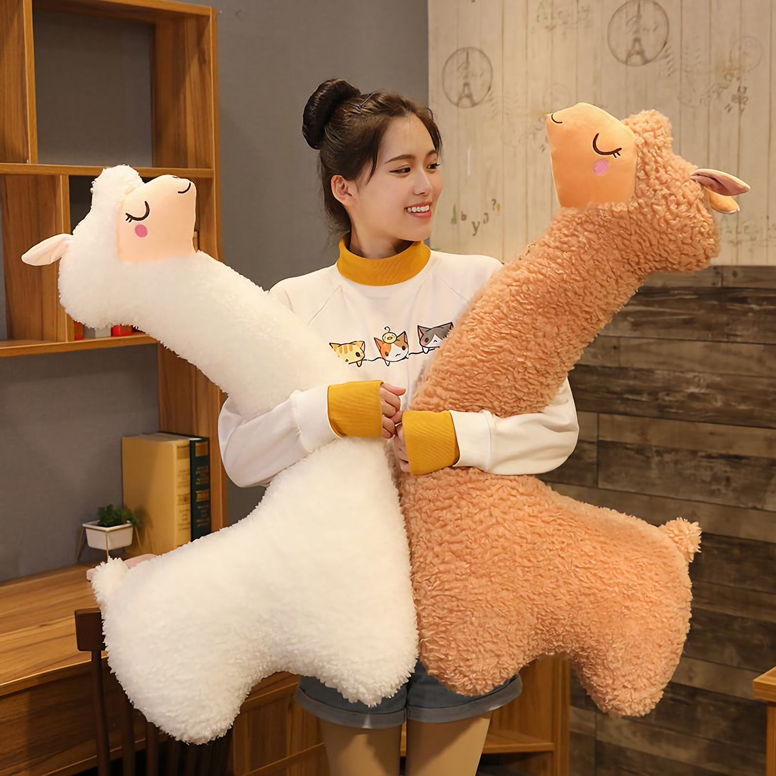 Woman smiling while hugging a white and a brown long alpaca plush pillow