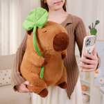 Woman holding a lotus leaf capybara plush and taking a phone photo