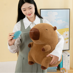 Woman holding a brown capybara plush and pulling its blue nose bubble