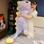 Woman in a white dress hugging a tall pink and blue rainbow dinosaur plush