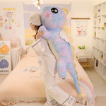 Woman holding a tall blue and pink rainbow winged dragon plush in a pastel bedroom