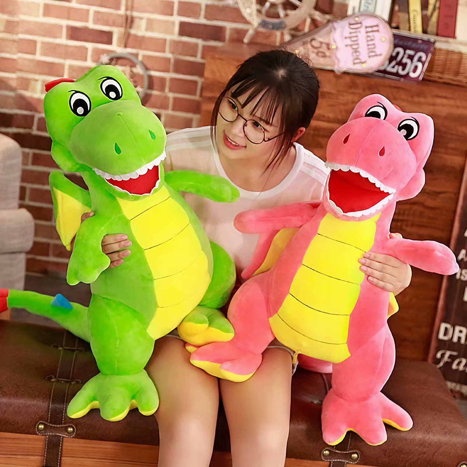 Woman with glasses holding a green Pterosaur plush and a pink Pterosaur plush