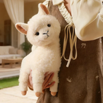 Woman in a brown dress holding a white fluffy alpaca plush