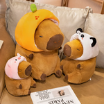 Capybara plushies in orange, pig and panda hoods on a sofa
