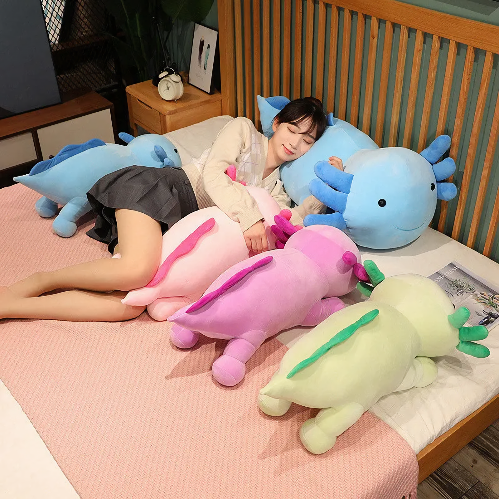 Girl lying on a bed with pink, purple, blue and green axolotl plush pillows around her