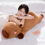 Woman resting her head on a brown lying capybara plush pillow