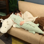 Woman hugging mint green dragon plush on sofa.