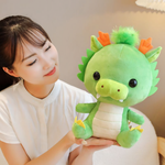 Woman holding a green dragon plush with orange horns and a lime snout, sitting upright.