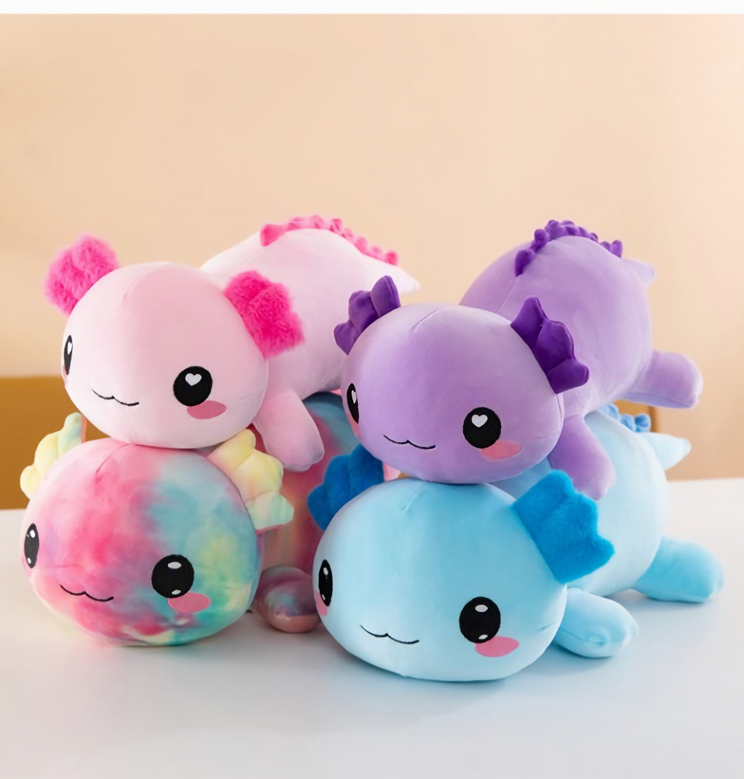 Stack of pink, rainbow, purple and blue axolotl plush pillows with smiling faces
