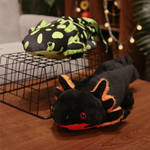 Spotted green and black axolotl plushies on a wire rack on a wooden table