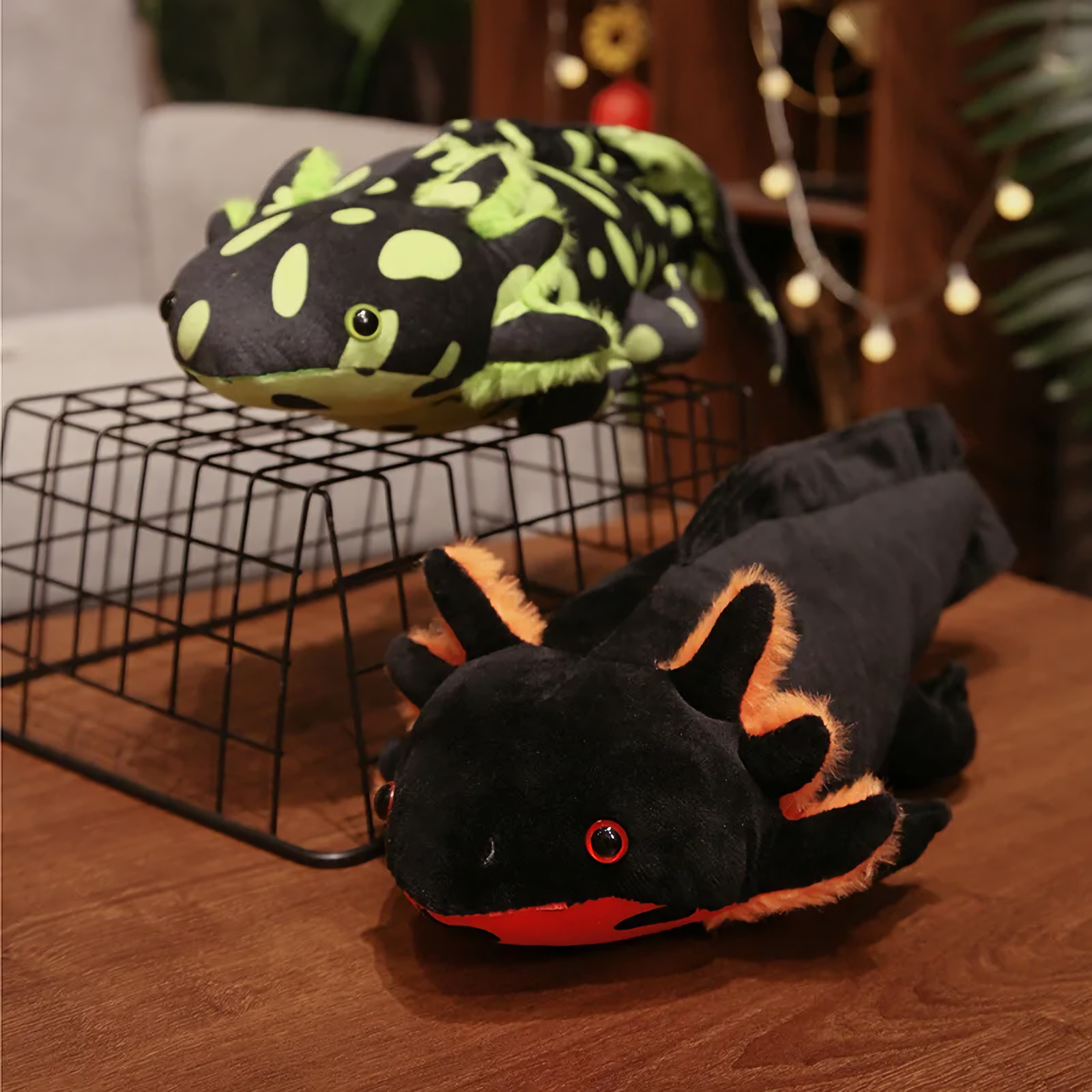 Spotted green and black axolotl plushies on a wire rack on a wooden table