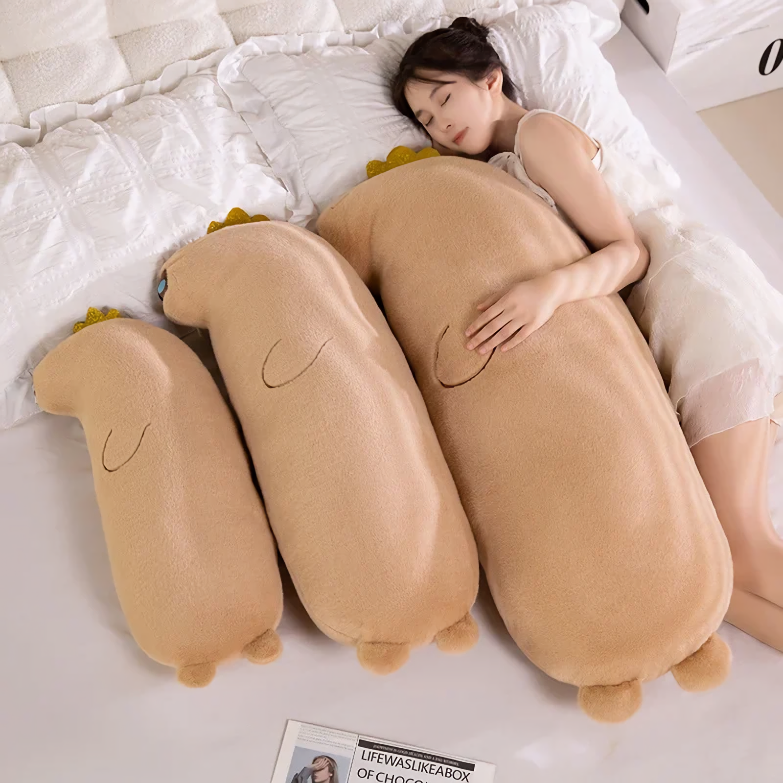 Woman sleeping beside three long tan capybara body pillows in different sizes