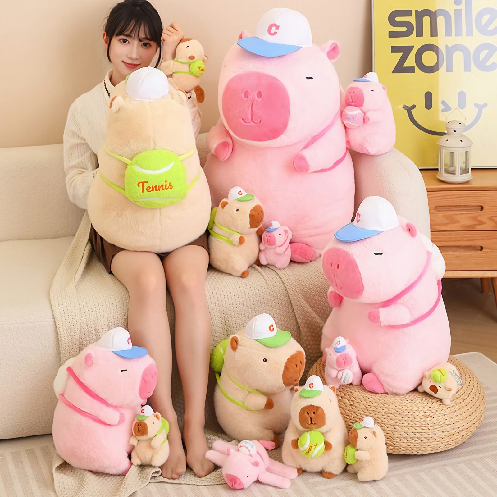 Woman sitting with a large brown capybara plush with a tennis bag and pink capybara plushies