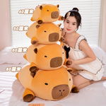 Size comparison of four stacked capybara plush pillows marked 40cm, 50cm, 60cm and 80cm beside a woman