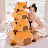 Size comparison of four stacked capybara plush pillows marked 40cm, 50cm, 60cm and 80cm beside a woman