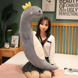 Woman sitting on a bed hugging a curved gray sea lion plush body pillow